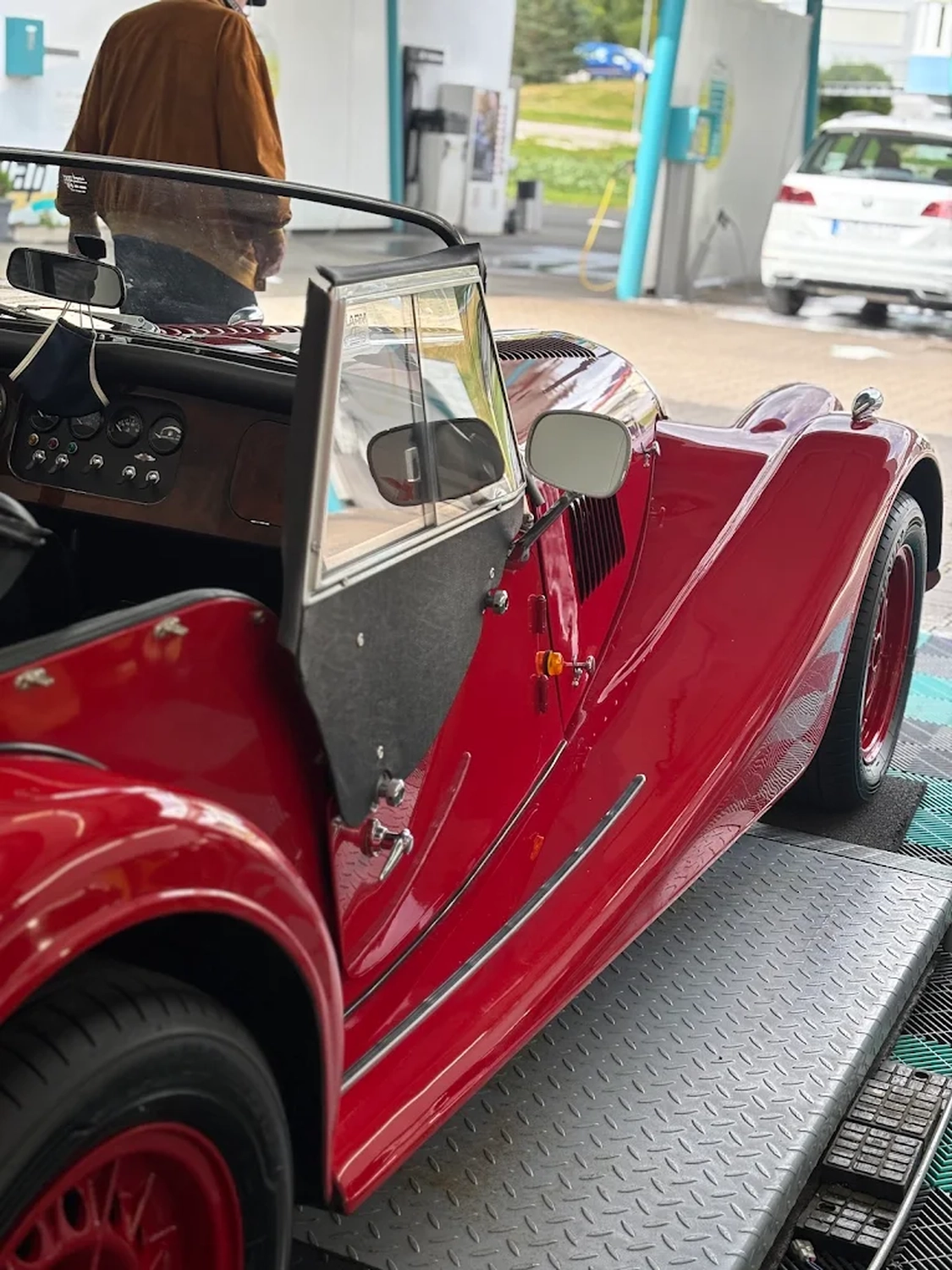 Simons Garage - Fahrzeugaufbereitung - Ein roter Oldtimer-Cabrio-Sportwagen auf einer Hebebühne.