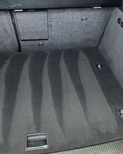 Simons Garage - Fahrzeugaufbereitung - Frisch gesaugter grauer Autoteppich mit abwechselnd dunklen und hellen Reinigungsstreifen.