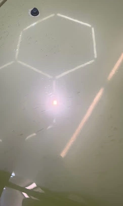 Simons Garage - Fahrzeugaufbereitung - Draufsicht auf eine helle Fläche mit einem beleuchteten, weißen, geometrischen Wabenmuster und einem zentralen Lichtpunkt.