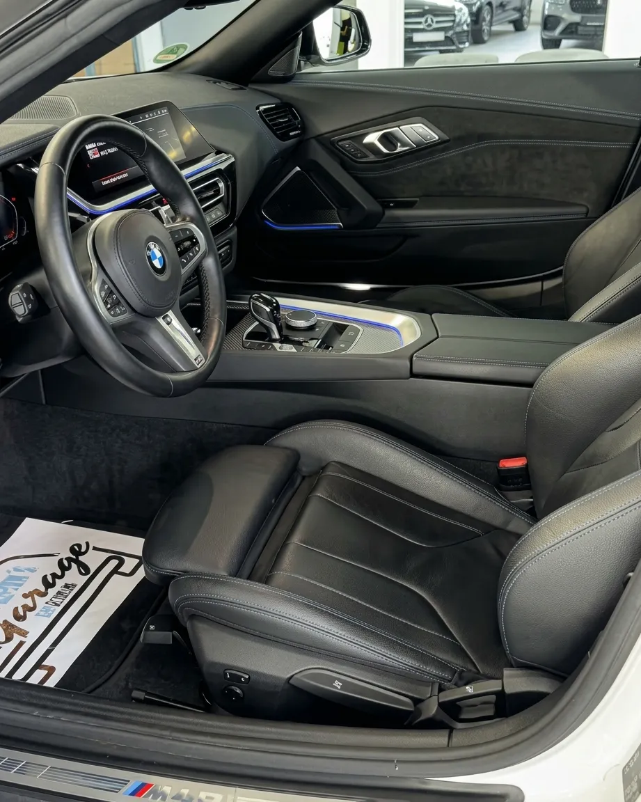 Simons Garage - Fahrzeugaufbereitung - Ansicht des Innenraums eines BMW mit schwarzer Lederausstattung, Fahrersitz, Lenkrad und Mittelkonsole.
