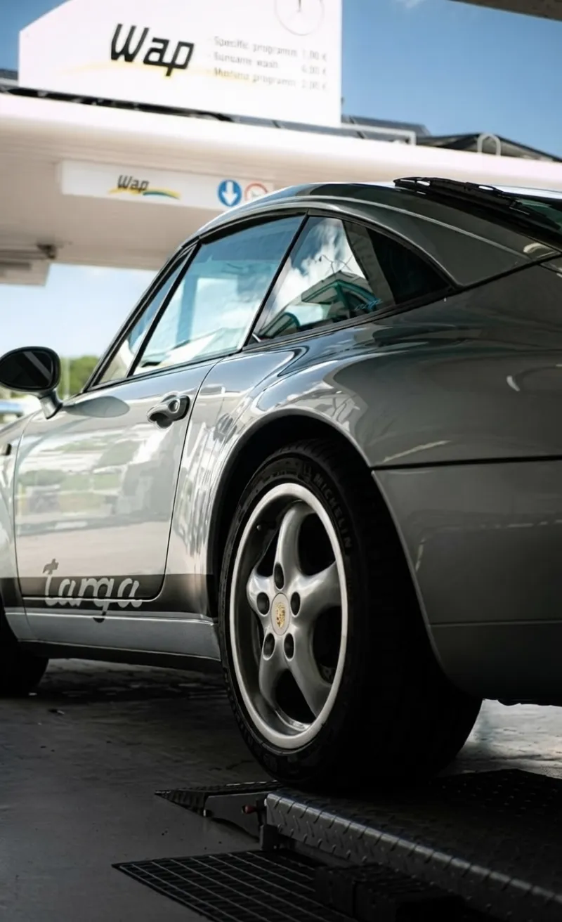 Simons Garage - Fahrzeugaufbereitung - Seitenansicht eines silbernen Porsche 911 Targa mit schwarzem Schriftzug.
