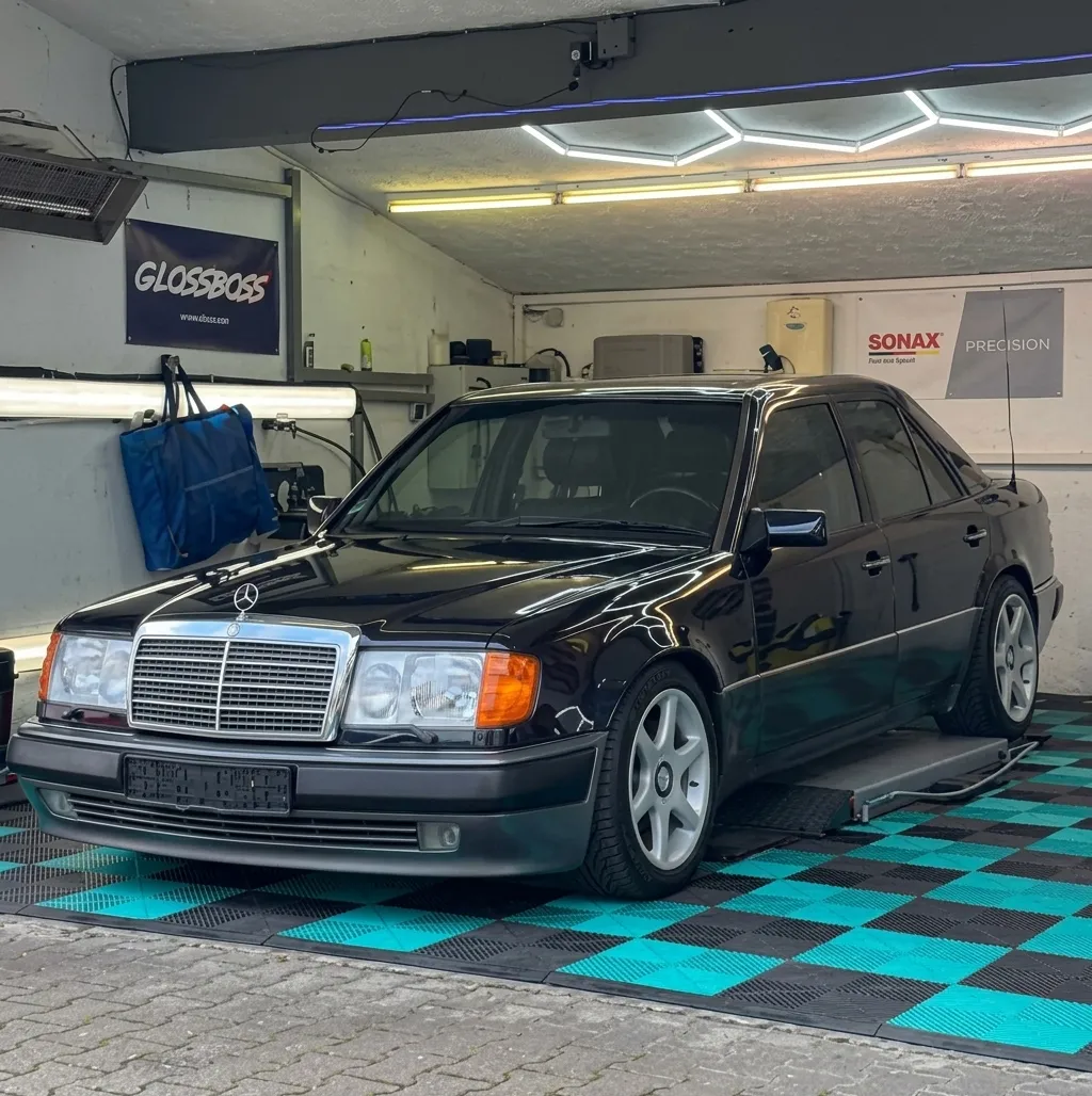 Simons Garage - Fahrzeugaufbereitung - Eine klassische schwarze Mercedes-Benz Limousine in einer hell erleuchteten professionellen Fahrzeugaufbereitungswerkstatt.