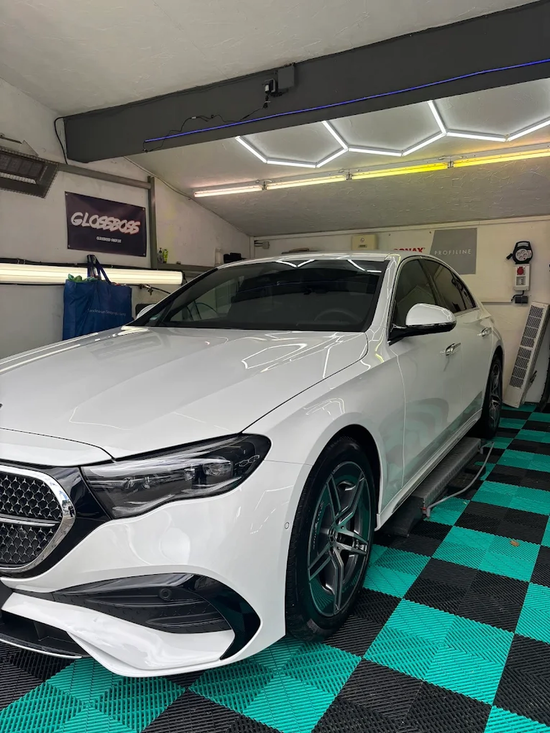 Simons Garage - Fahrzeugaufbereitung - Weiße Mercedes-Benz Limousine in einer Aufbereitungsbucht unter professioneller Beleuchtung.