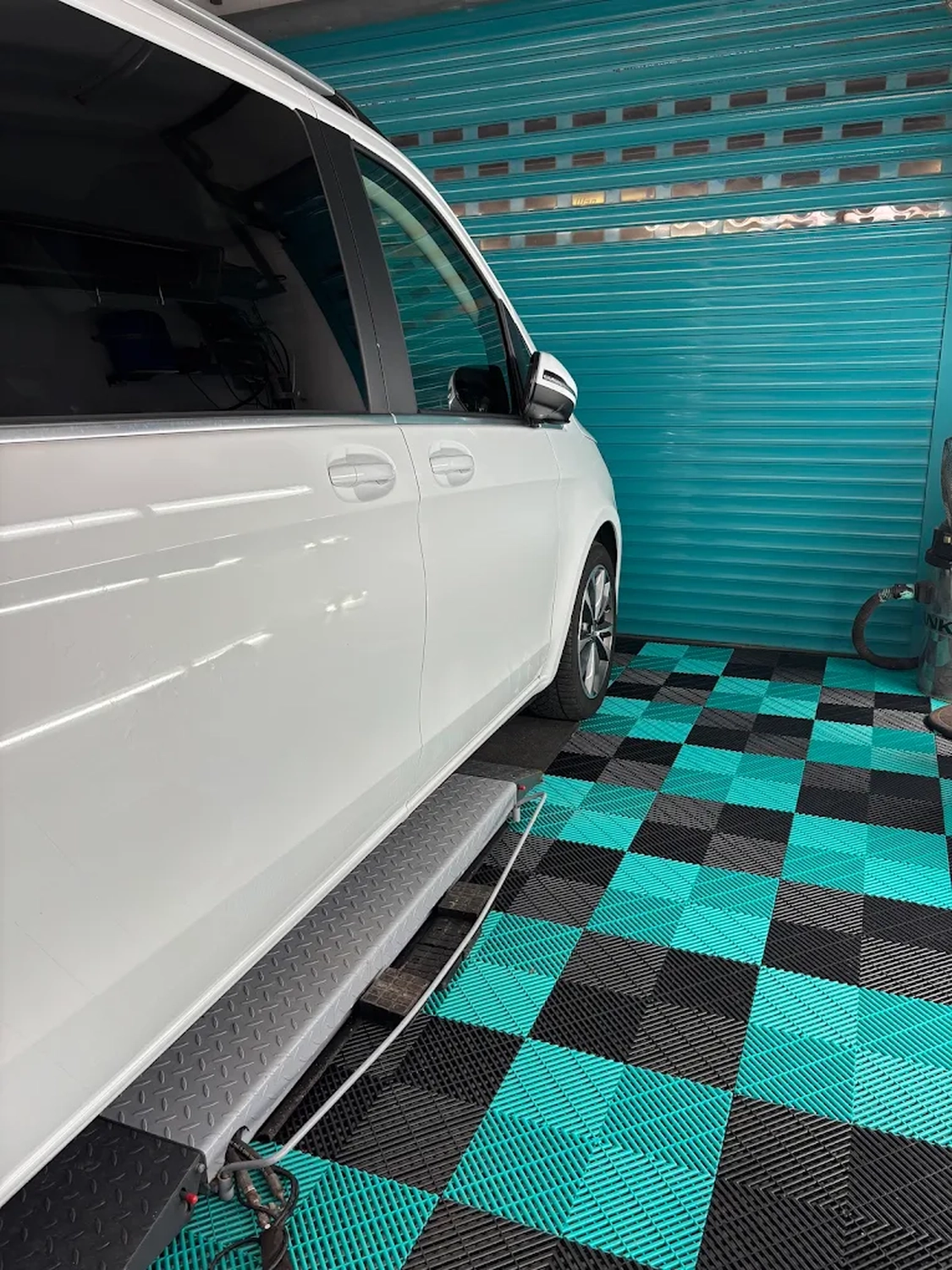 Simons Garage - Fahrzeugaufbereitung - Seitenansicht eines weißen Autos auf Schachbrettboden.