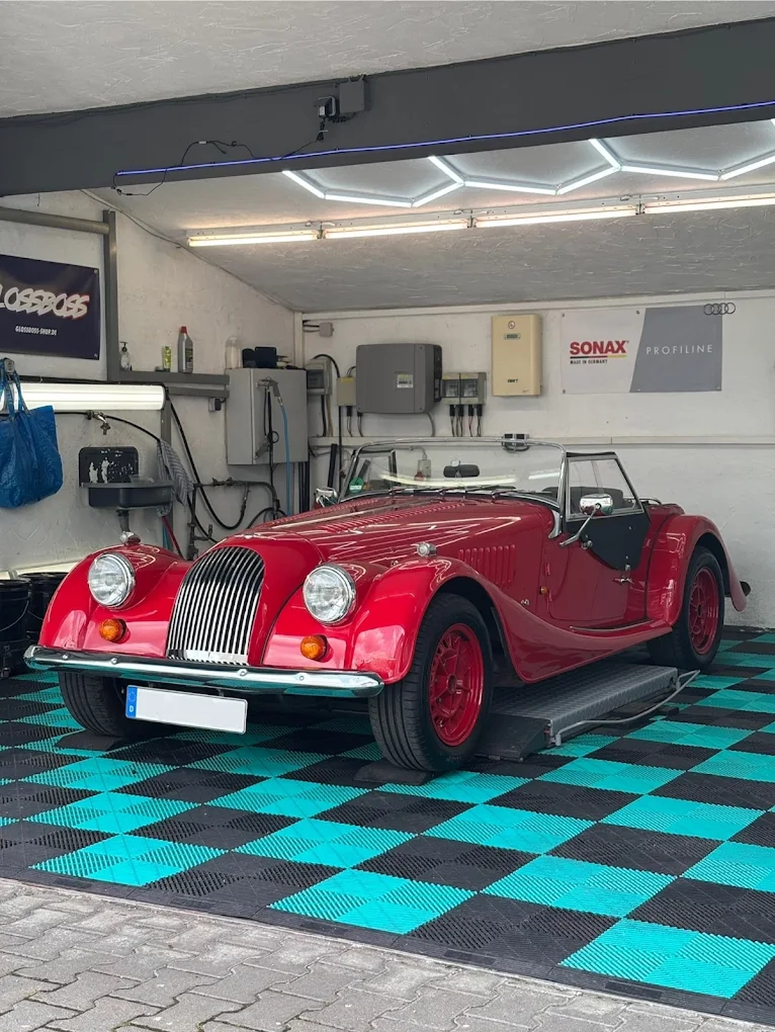 Simons Garage - Fahrzeugaufbereitung - Ein klassischer roter Morgan-Sportwagen in einer Garage.